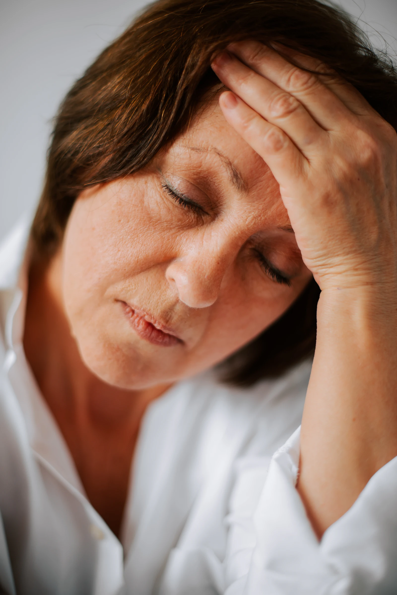 Woman easing a tension headache with her hand to her temple